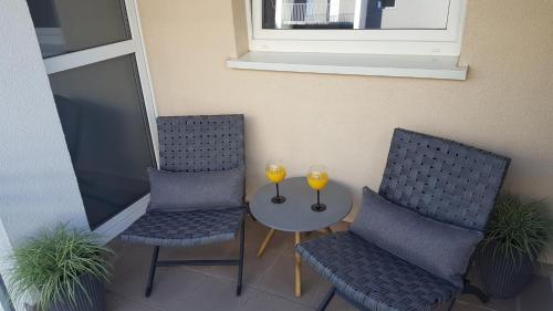 two chairs and a table with two wine glasses on it at Apartament NAD MALTĄ in Poznań