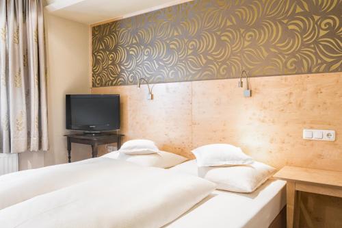 two beds in a hotel room with a tv at Rosa Canina Superior in Sankt Anton am Arlberg
