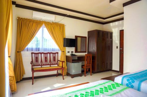 a bedroom with a bed and a desk and a chair at Veranda Suites and Restaurant in Paoay