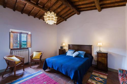 a bedroom with a blue bed and a chandelier at San Casciano - Appartamenti Podere Ianni in San Casciano in Val di Pesa