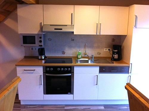 a kitchen with white cabinets and a stove and a sink at Urlaubsdomizil im Grünen in Westerstede