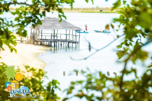 a beach with a pier and people on the water at Dinuda Resort in Kalpitiya