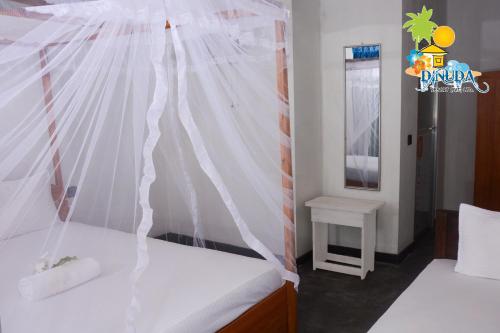 a bedroom with a bed with a canopy at Dinuda Resort in Kalpitiya