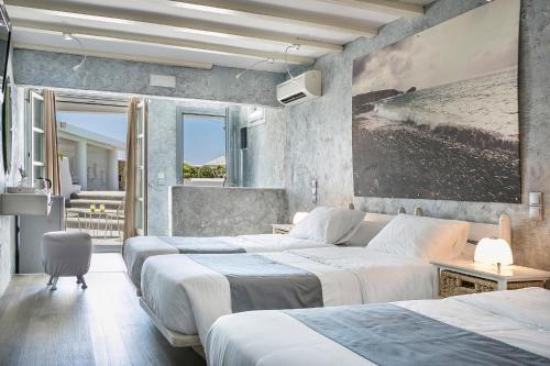 a hotel room with three beds and a balcony at Ilio Maris in Mýkonos City