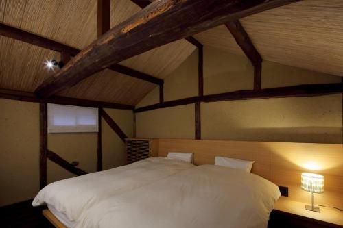 1 dormitorio con 1 cama blanca grande en el ático en 滔々 御崎 町家の宿 toutou Onzaki Machiya no Yado, en Kurashiki