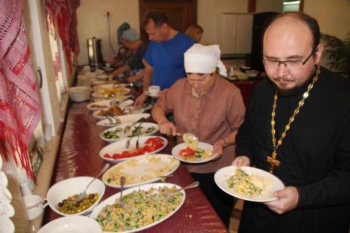 a group of people standing around a table with plates of food at Russian Pilgrim Residence in Sowayma