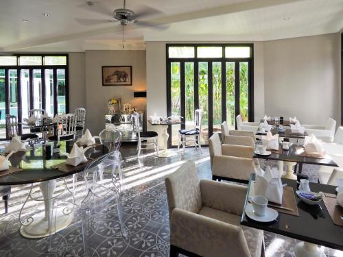 a living room with tables and chairs and windows at Hua Chang Heritage Hotel in Bangkok