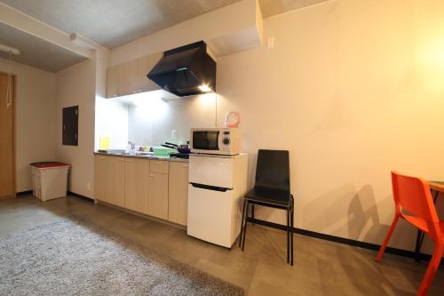 a kitchen with a white refrigerator and a microwave at Exsaison House Imamiya 201 in Osaka