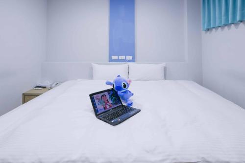a stuffed animal sitting on top of a bed with a laptop at Mei Ti Fashion Hotel in Zhongli