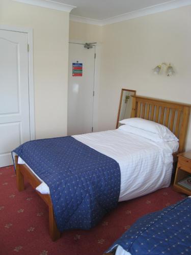 a bedroom with a bed with a blue and white comforter at Herdshill Guest House in Wishaw