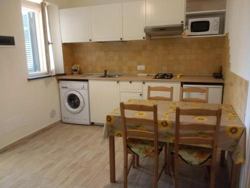 cocina con mesa y lavadora en Casa Papaveri Rossi, en Finale Ligure