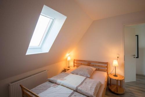 a bedroom with a bed with a window and two lamps at FEWO Maisonettenwohnung in Steinkirchen