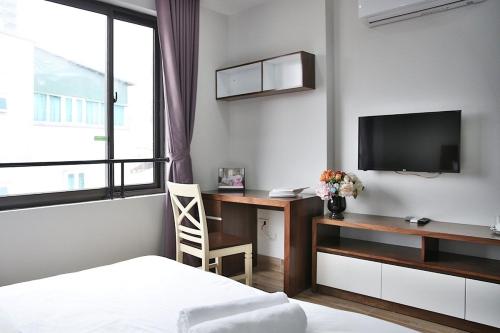 a bedroom with a desk and a tv and a bed at V House 6 Serviced Apartment in Hanoi