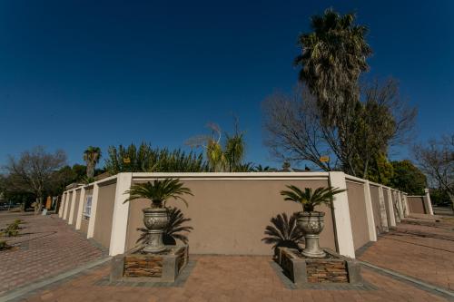 a white wall with two potted plants next to it at Royl Court Guesthouse in Kimberley