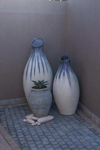 three vases sitting on a tiled floor with a plant at Royl Court Guesthouse in Kimberley