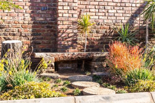 a brick wall with a bench in a garden at Royl Court Guesthouse in Kimberley