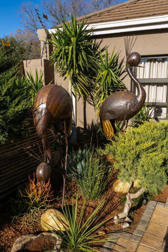 two large bronze statues of birds in a garden at Royl Court Guesthouse in Kimberley