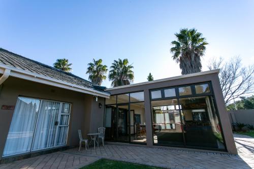 a house with sliding glass doors and palm trees at Royl Court Guesthouse in Kimberley