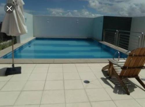 una piscina con una silla y una piscina en Apartamento na Ponta Verde en Maceió