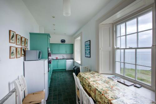 cocina con armarios verdes y nevera blanca en Galley Head Lightkeeper's Houses, en Donoure