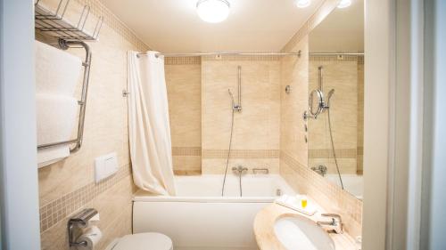 a bathroom with a tub and a toilet and a shower at Hestia Hotel Jugend in Rīga