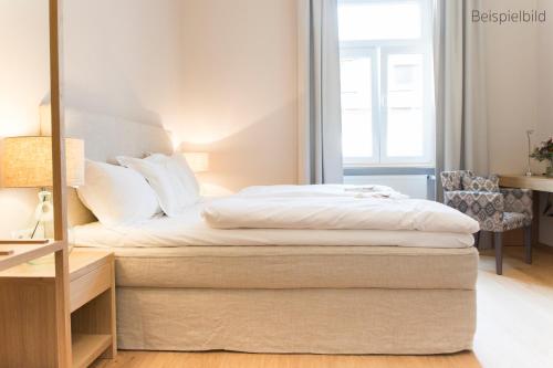 Schlafzimmer mit einem Bett mit weißer Bettwäsche in der Unterkunft Cottage Rheingau Hotel in Walluf