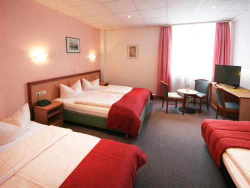 a hotel room with two beds and a desk at Hotel Constantin in Trier