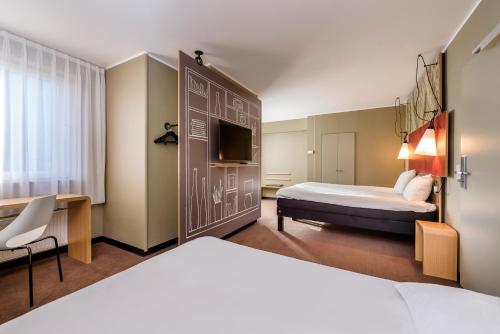 a hotel room with two beds and a tv at ibis Lille Centre Grand Palais in Lille