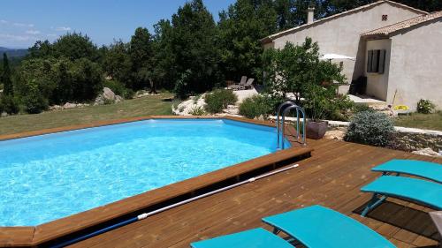 een zwembad met blauwe stoelen op een houten terras bij Lou Mazet in Saint-Privat-de-Champclos