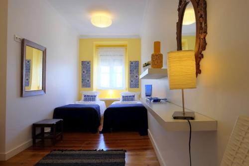 リスボンにあるLisbon Lights Apartmentsのベッド2台、鏡、ランプが備わる客室です。
