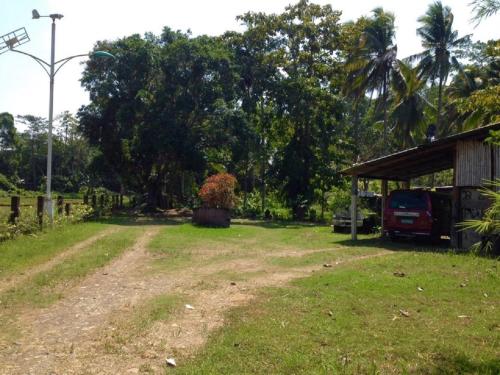 a dirt road next to a shed with a car parked at Bambua Nature Cottages in Puerto Princesa City