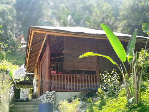 a small wooden cabin with a porch in a garden at Victordelia Hilltop Hostel in San Vicente