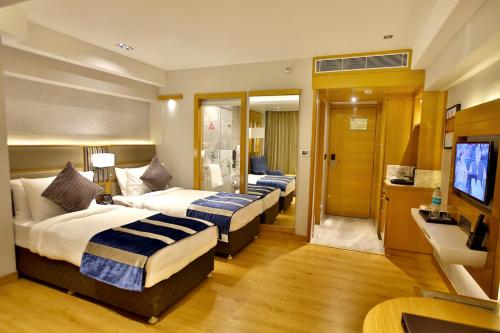 a hotel room with three beds and a television at Regenta Central the Crystal Kanpur, in Kānpur