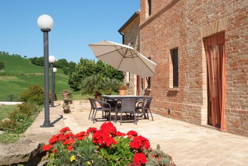 a patio with a table and an umbrella and flowers at Collerovere Country House in SantʼAngelo in Pontano
