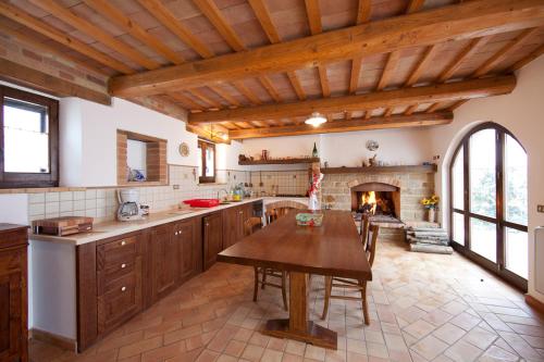 a kitchen with a wooden table and a fireplace at Collerovere Country House in SantʼAngelo in Pontano