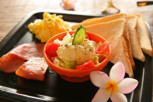 a black plate with a bowl of food and a flower at Kenting Afei Surf Hostel Jialeshuel Nanu in Manzhou