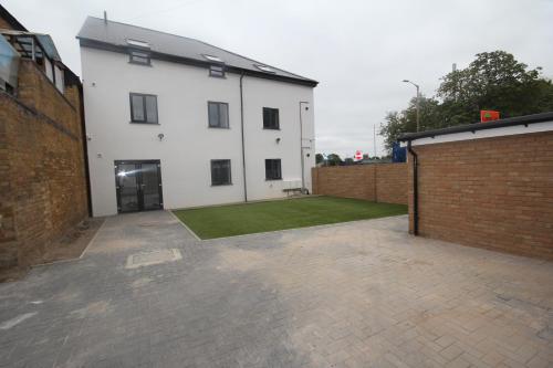 a white building with a lawn in a courtyard at Holden Court Apartments -Apt 4 in West Drayton