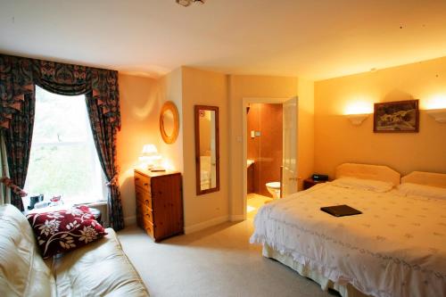 
a hotel room with a bed, chair, and nightstand at Ilkley Riverside Hotel in Ilkley
