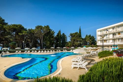 een zwembad met stoelen en parasols en een hotel bij Aminess Laguna Hotel in Novigrad Istria