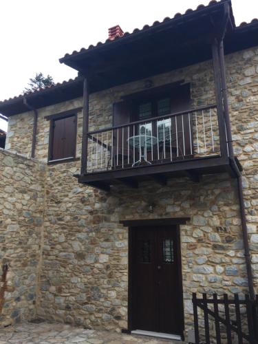 a stone house with a balcony and a deck at Apostolia's Small House Bed and view in Anavrití