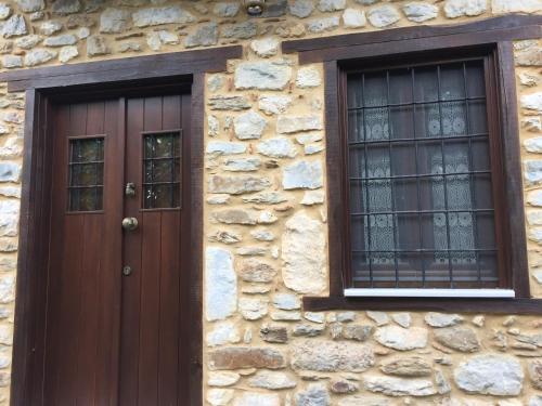 a building with a wooden door and two windows at Apostolia's Small House Bed and view in Anavrití
