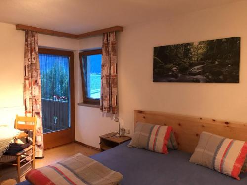 een slaapkamer met een bed en een groot raam bij Ferienwohnungen Taxacher in Fügen