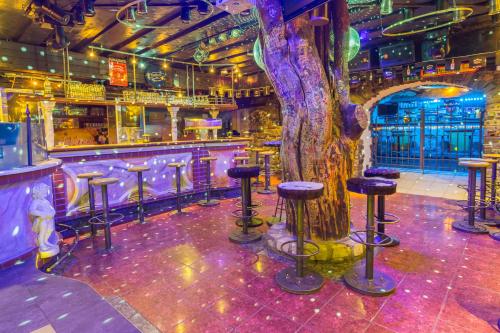a bar with stools and a tree in the middle at Party Hotel Taverne in Obertauern