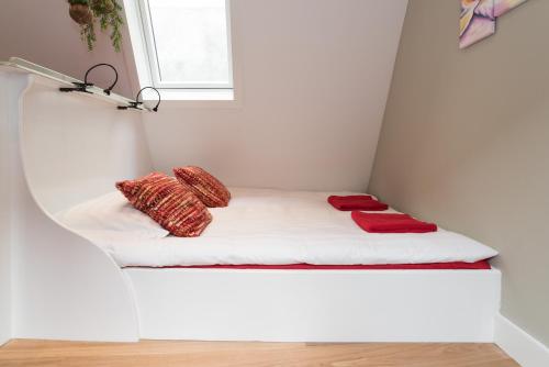 a small room with a bed with red pillows on it at Saint Claire Studio's in Amsterdam