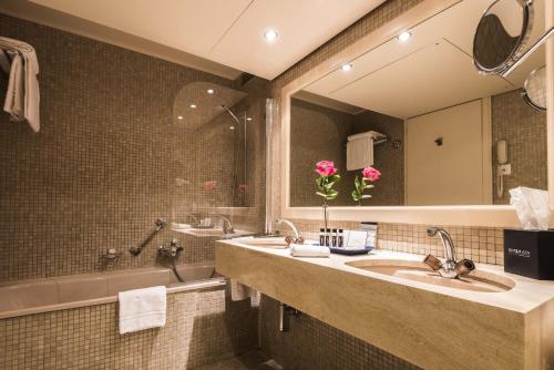 a bathroom with two sinks and a tub and a mirror at Royal Plaza Montreux in Montreux