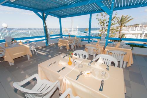 a restaurant with white tables and chairs and the ocean at El Mouradi Club Selima in Port El Kantaoui