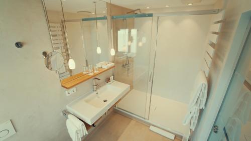 a white bathroom with a shower and a sink at Hotel Adler Asperg in Asperg