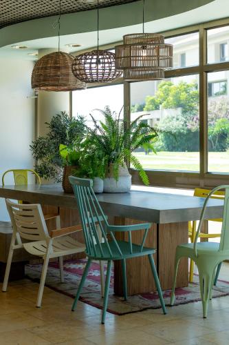 a dining room table with chairs and potted plants at Shefayim Kibbutz Hotel in Kibbutz Shefayim