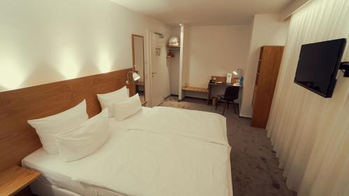 a hotel room with a bed with white sheets and pillows at Hotel Adler Asperg in Asperg