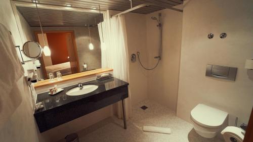 a bathroom with a sink and a toilet and a mirror at Hotel Adler Asperg in Asperg